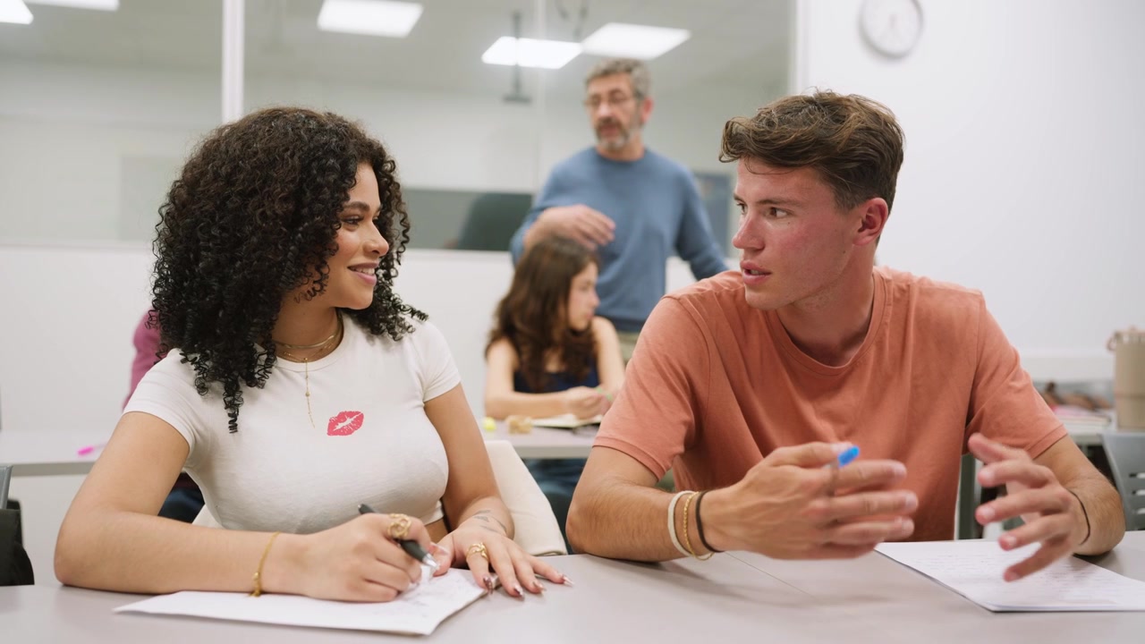 Junge Studenten unterhalten sich und machen sich Notizen in einem Klassenzimmer.