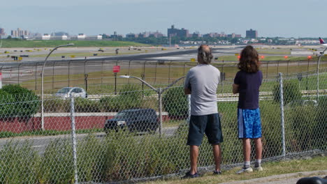 american airlines jet taxis on runway at laguardia airport with father and son watching from public park