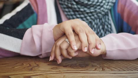 woman's hands with a ring on a wooden table