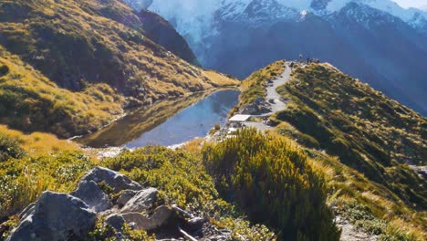 panorama shot of beautiful mountains with hiker reaching peak and enjoying view of snowy summits during bright sunny day - mueller hut route,mount cook national park