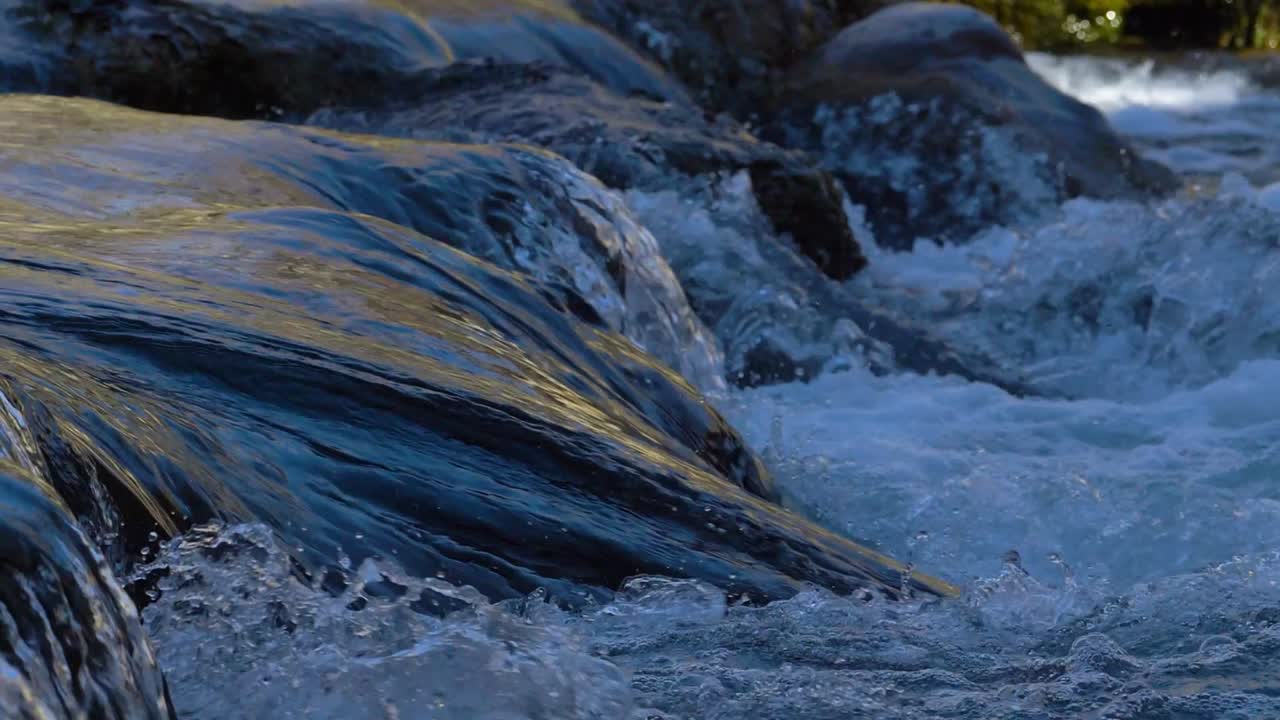 Ein Fluss fließt schnell unter einer Brücke an einem kühlen und sonnigen Tag.