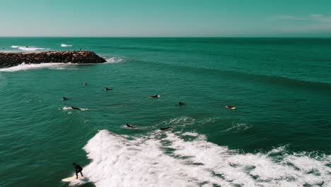 toma aérea de un grupo de surfistas montando olas juntos, ericeira, portugal