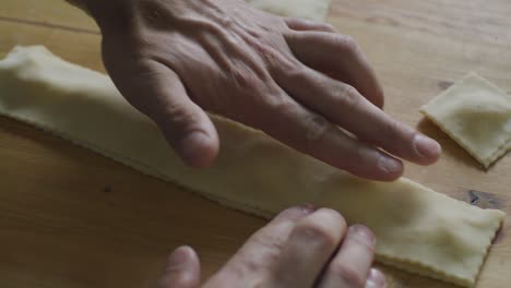 hands pressing folded dough as cooking homemade italian pasta