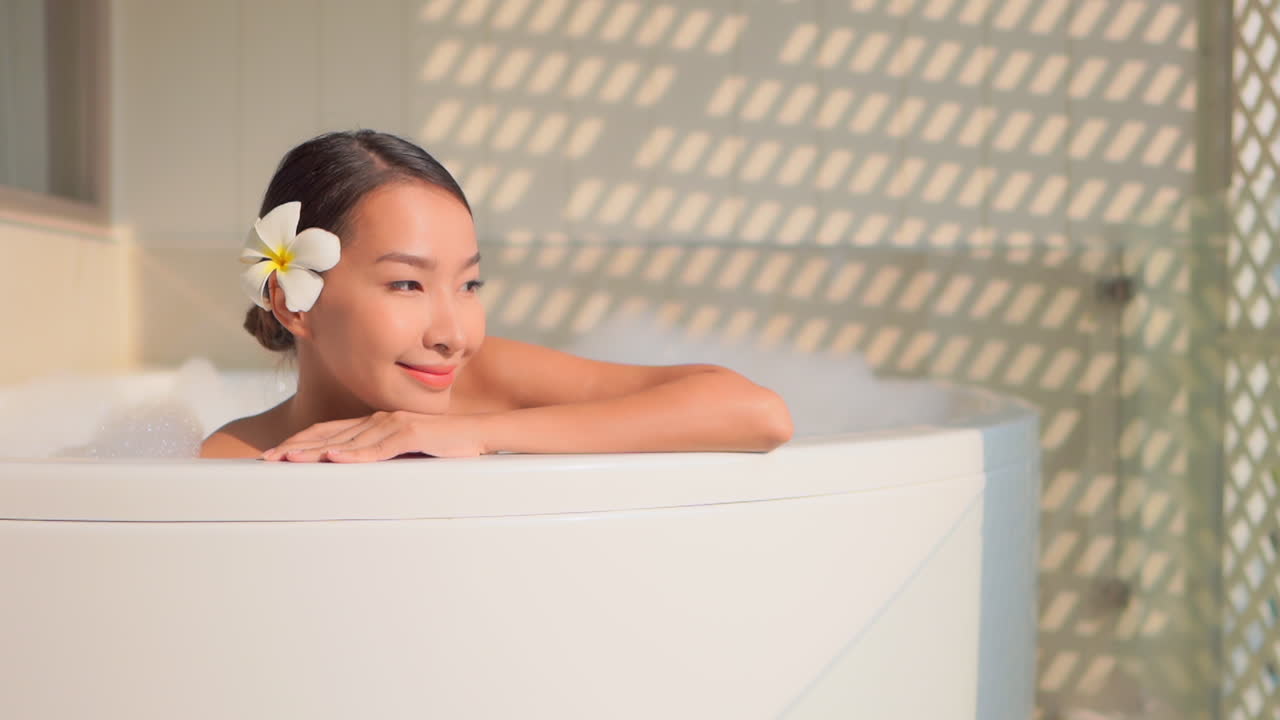 Pretty young Asian woman on holiday enjoys warm bath in luxury resort