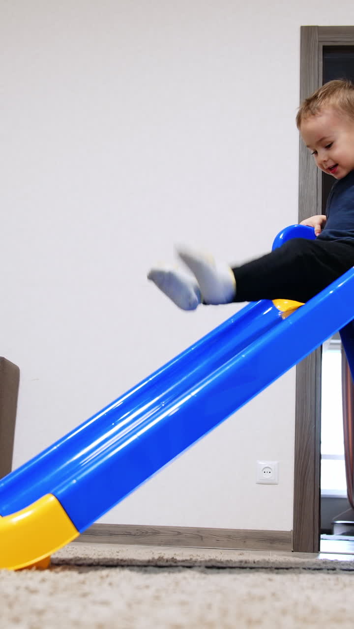 Sliding playground small boy. Colorful kindergarten active play. Vertical video
