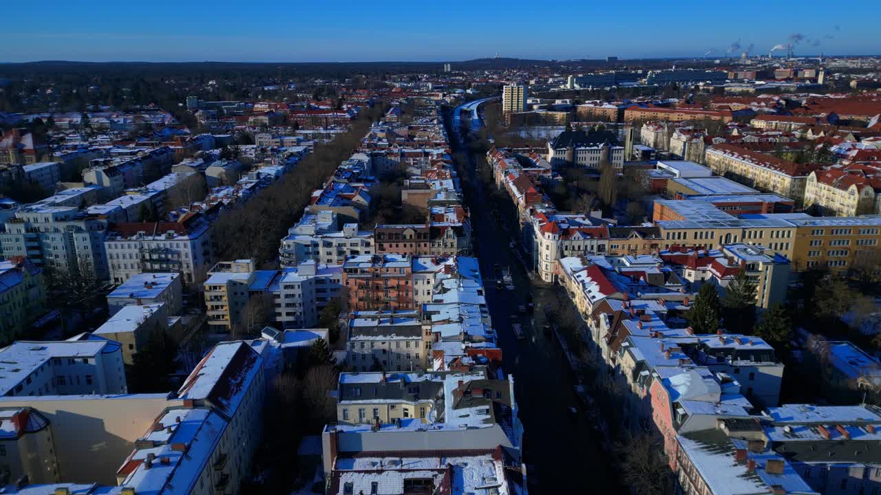 Panoramica della città di Berlino vista dall'alto, che mostra tetti innevati, edifici urbani e strade sotto un cielo azzurro brillante. Vista aerea fluida con panorama statico da drone in hovering