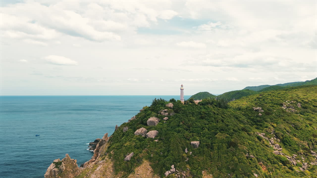 Ảnh quay bằng drone chuẩn điện ảnh về ngọn hải đăng trắng lịch sử ở Mũi Đại Lãnh, nằm trên những ngọn núi xanh tươi nhìn ra Biển Đông xanh dưới bầu trời tươi sáng