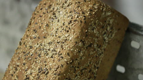 close up view of a brown loaf bread with sesame seeds rest on a baking tray in the bakery. - pan down, slow motion