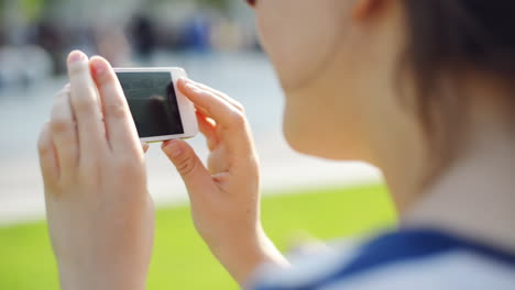 woman filming mobile cell phone in city park