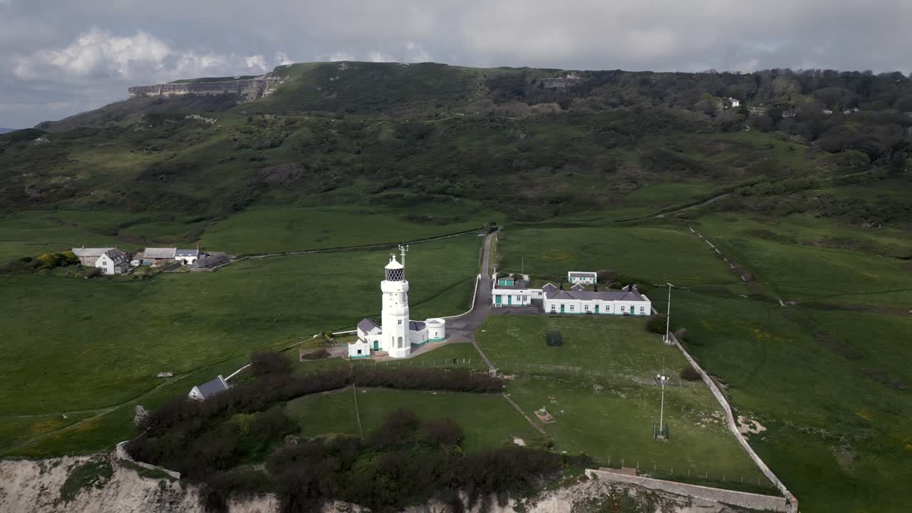 Drone spinning around St. Catherine’s Lighthouse on green coast, sunny day