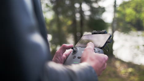 hombre caucásico que opera un dron dji en un control remoto en la naturaleza