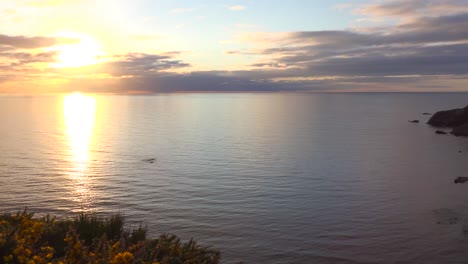 pan shot from setting sun to a small scottish coastal fishing village