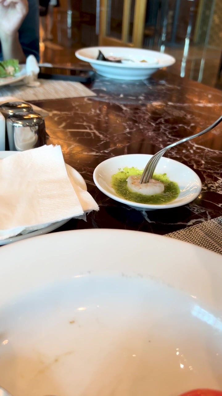 A fork picks up a shrimp and dips it into spicy green chili sauce