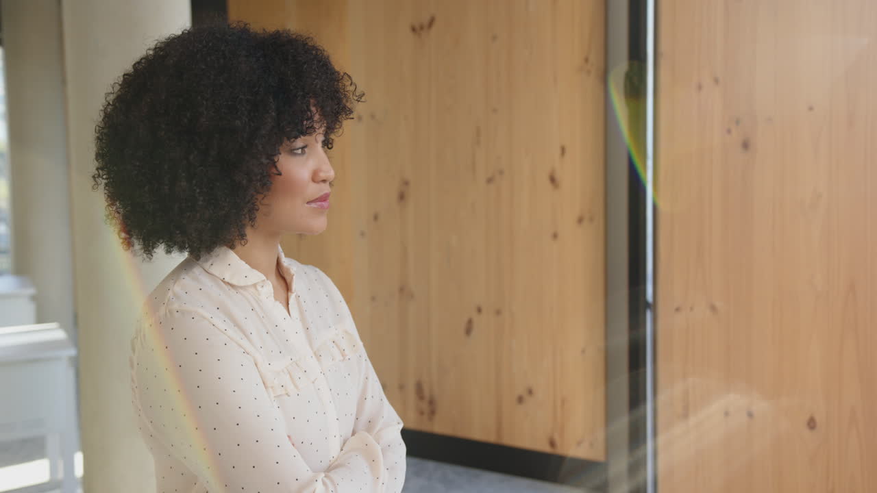 Smiling businesswoman with curly hair standing confidently in modern office