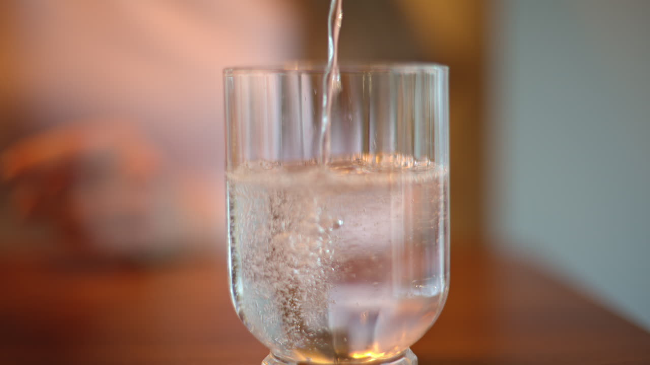 Woman pouring sparkling water in glass
