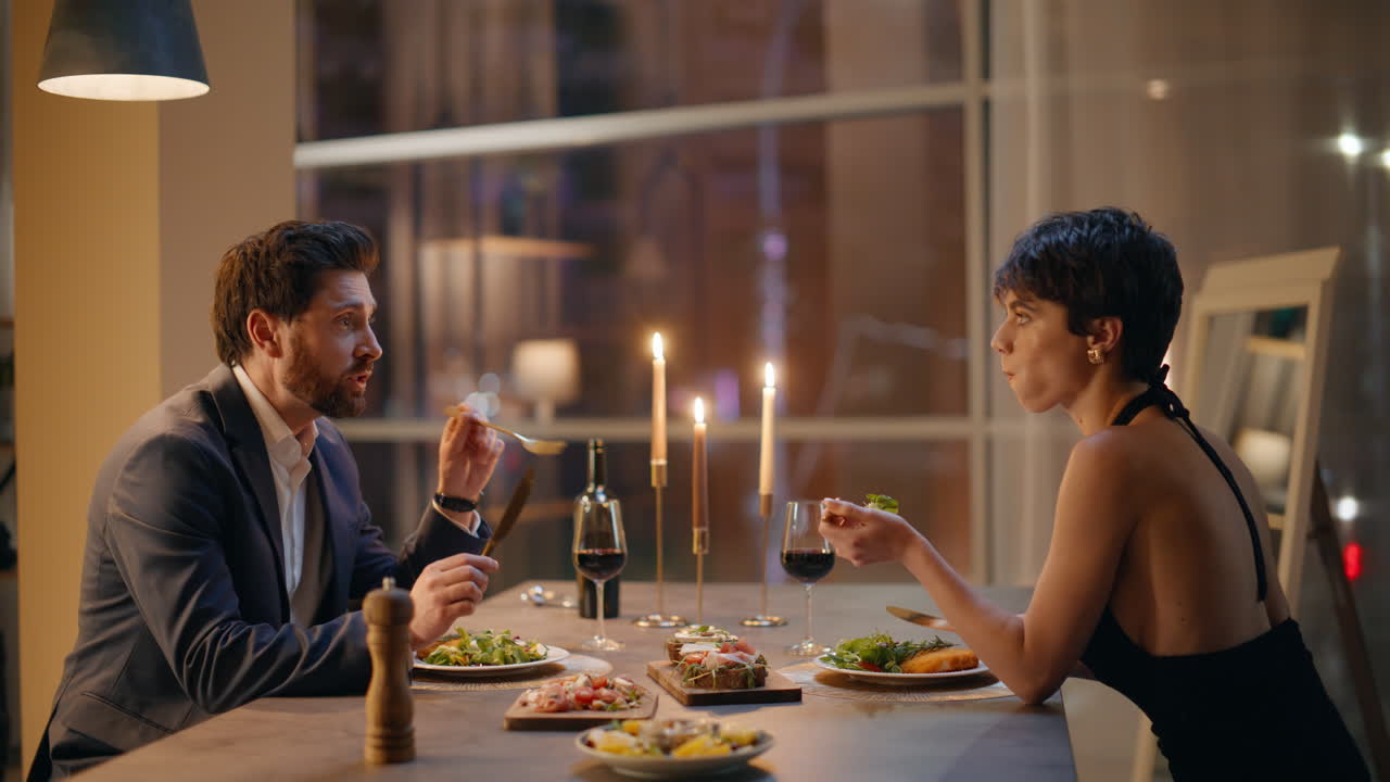 Coppia che parla in un ristorante di notte, seduta in luce dorata, primo piano. Coppia romantica