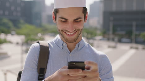 Retrato-De-Un-Joven-Musulmán-Atractivo-Relajado-Usando-La-Tecnología-De-Un-Teléfono-Inteligente-Enviando-Mensajes-De-Texto-Navegando-Por-Una-Aplicación-De-Redes-Sociales-En-Una-Ciudad-Urbana-Soleada-Usando-Kufi