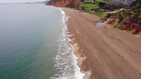 Amazing-4K-Aerial-slow-and-steady-descending-towards-the-oceans-edge-and-rolling-waves-of-Branscombe-Beach