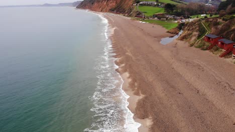 amazing 4k aerial slow and steady descending towards the oceans edge and rolling waves of branscombe beach