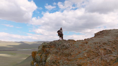 un cazador de águilas en la cima del acantilado en el oeste de mongolia - toma aérea de dron