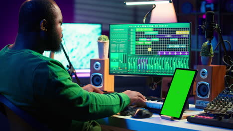 Songwriter-composer-mixing-and-mastering-tracks-next-to-green-screen