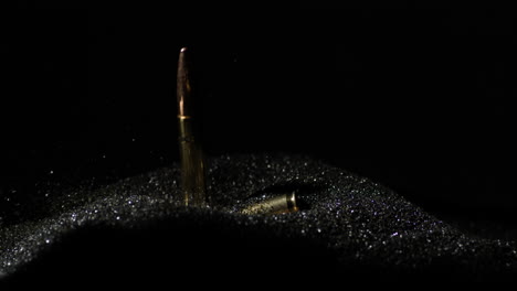 6mm arc bullets falling into gunpowder dust pile in slow motion, detail closeup