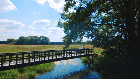 Girl-walking-over-a-little-bridge-in-the-area-of-Assen,-Netherlands