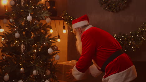 santa claus va al árbol de navidad y pone una gran caja hermosa con un regalo para un niño obediente. imágenes de alta calidad 4k