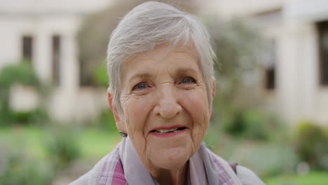 close up portrait of elderly caucasian woman smiling happy at camera enjoying sunny day in park