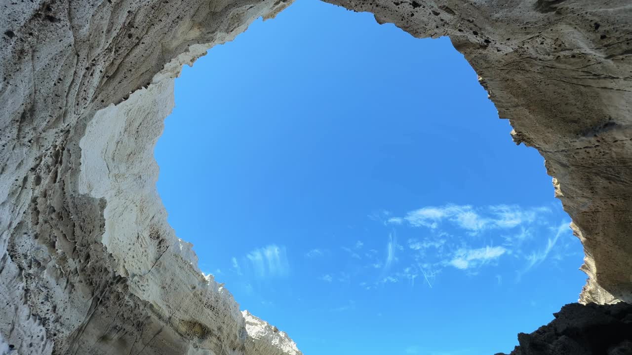 The entrance to Sikia Cave in Milos glows under the bright sun on a clear day