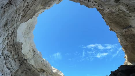 the entrance to sikia cave in milos glows under the bright sun on a clear day