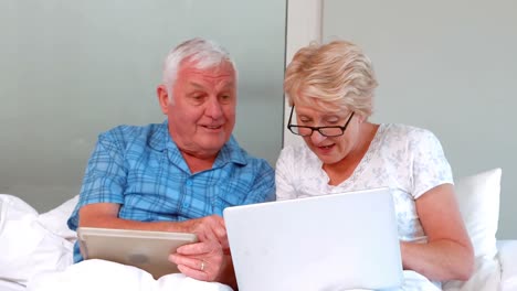 senior couple using tablet and laptop