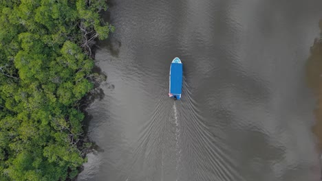 drone view of a blue-roofed boat navigating the calm waters of tamarindo estuary.