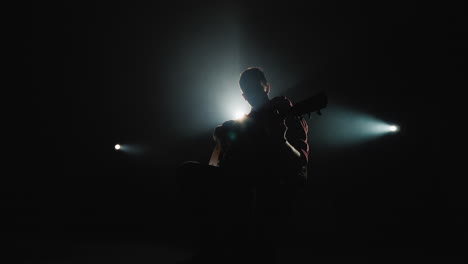 a young man plays the guitar sits on stage 5