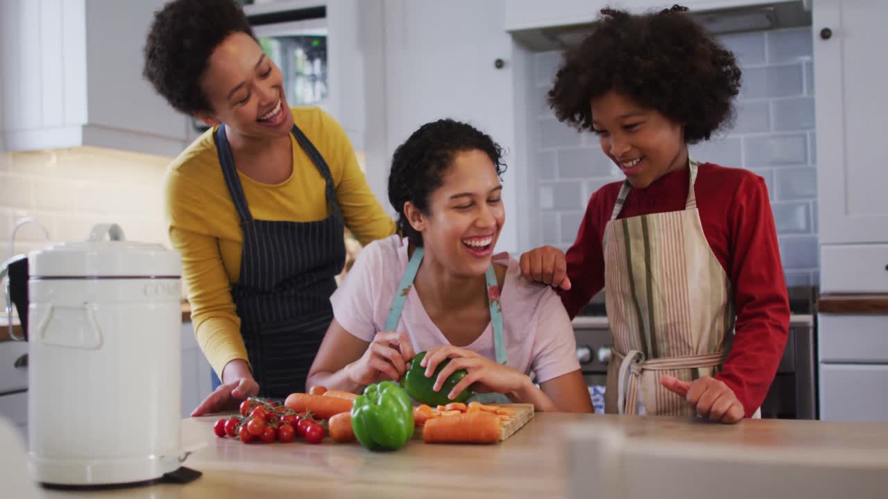 Mixed race lesbian couple and daughter preparing food in kitchen