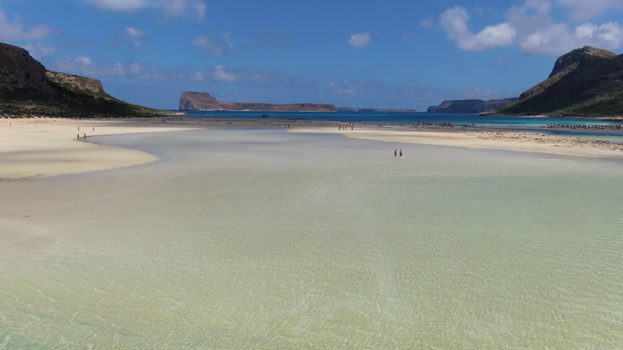 Balos Beach lagoon in Crete Greece with tourists enjoying their summer vacation, Aerial flyover reveal shot