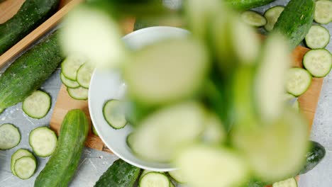 round slices of fresh cucumber fall into the bowl.