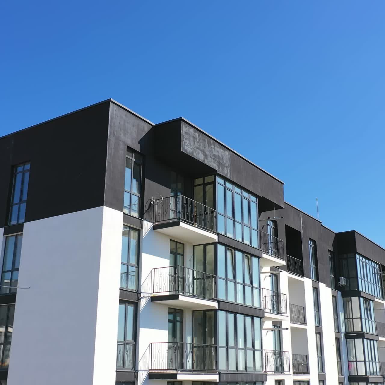 Beautiful design of multistorey building. New apartment with balconies against blue sky. Exterior of residential building