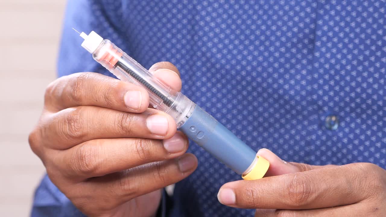 Persona che tiene una penna per insulina