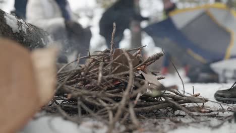 man starting small fire on snowy ground