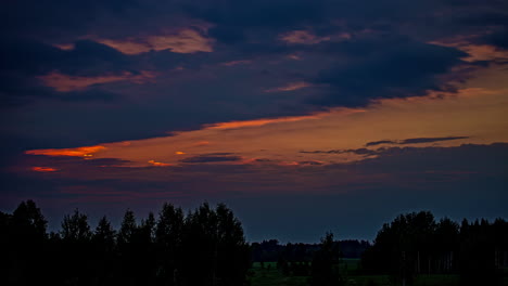 Statische-Aufnahme-Dunkler-Wolken,-Die-Im-Zeitraffer-über-Grünem-Wald-Entlang-Der-Wiesen-Im-Zeitraffer-Am-Abend-Vorbeiziehen