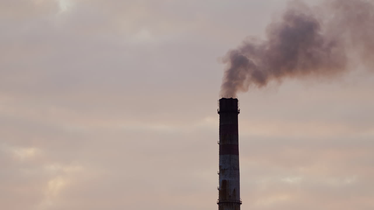 fabbrica buia contro il sole arancione che tramonta. tubi di fabbrica con fumo. fumo sporco si riversa fuori dai camini in aria sullo sfondo del fiume. video aerea.