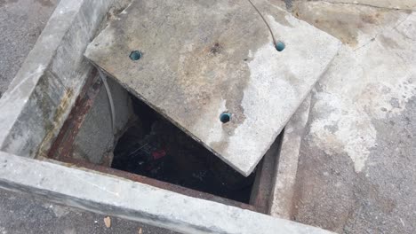 open manhole with rubbish stagnant water - concrete cover removed - high angle shot