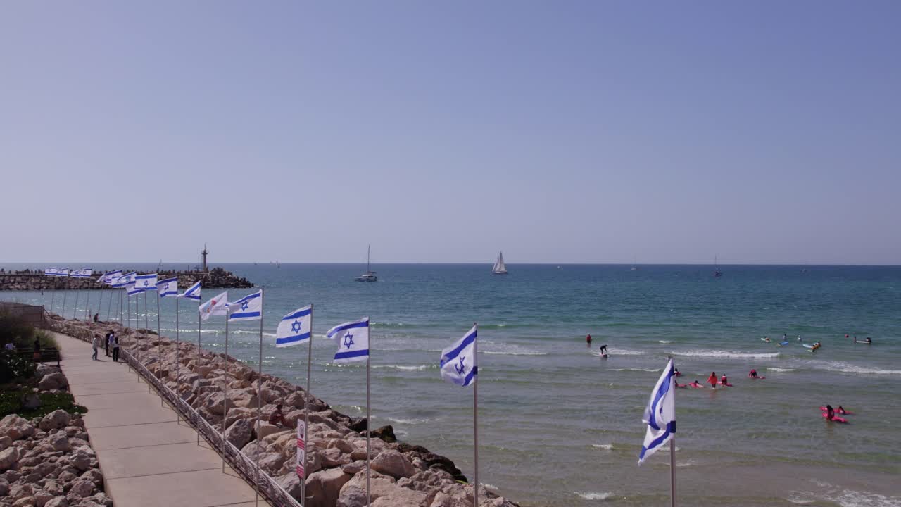 Israel flags waving with the ocean in the background in Marina Herzliya