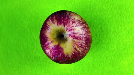 rotating apple on bright green background, showcasing its texture and color contrast