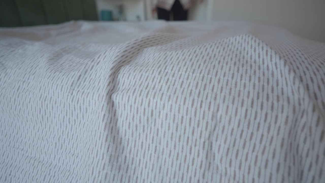 Making a bed with white linen sheets