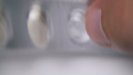 hombre toques con ampollas de plata de píldoras blancas en superficie clara