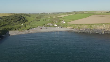 An-aerial-view-of-Abereiddi-beach-in-Pembrokeshire,-South-Wales,-on-a-sunny-evening-with-a-clear-blue-sky