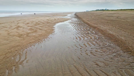 Aerial-video-footage-of-a-coastal-beach-scene-with-ocean,-sand-dunes-and-crashing-waves