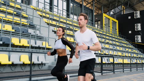 sportive couple running fast in the stadium